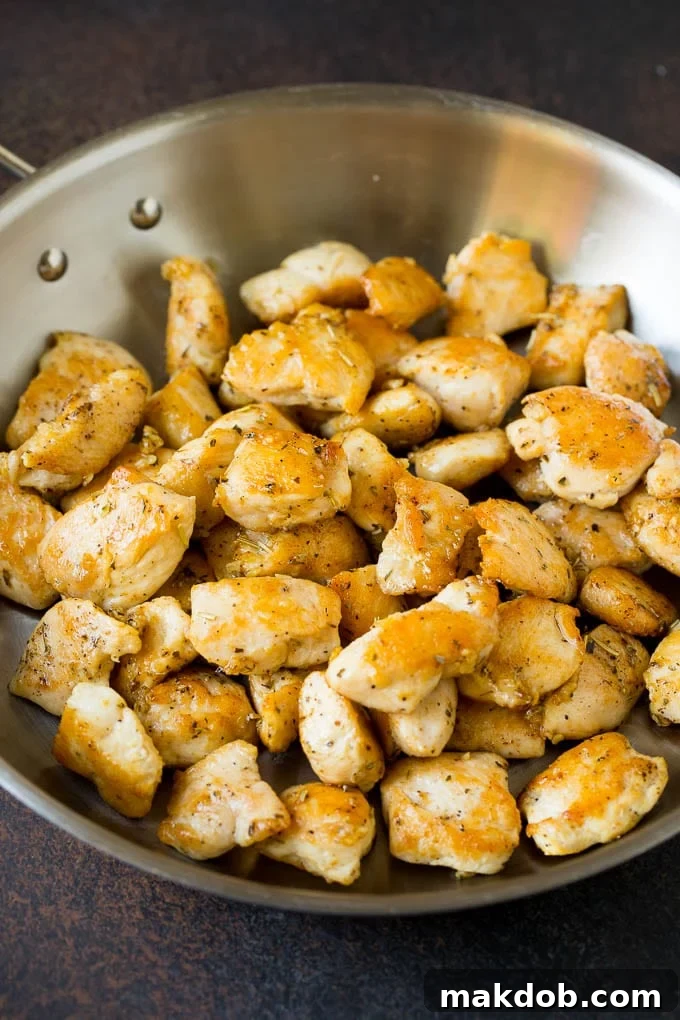 Perfectly diced and sautéed chicken in a skillet, ready for the pasta.