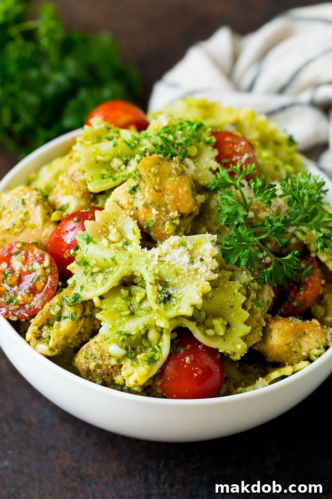 A beautifully presented bowl of chicken pesto pasta, garnished with fresh parsley.