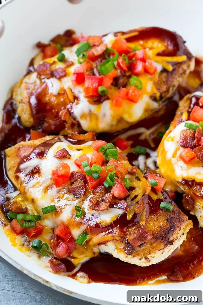 A skillet of Monterey chicken with seasoned cooked chicken breasts topped with barbecue sauce, two types of cheese and bacon.