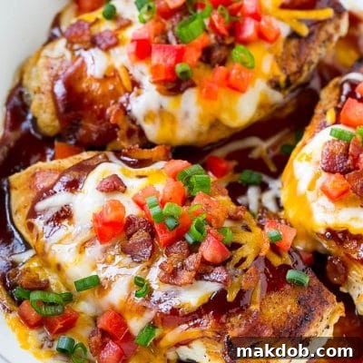 A skillet of Monterey chicken with seasoned cooked chicken breasts topped with barbecue sauce, two types of cheese and bacon.