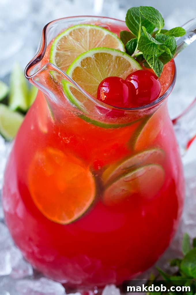 A pitcher of cherry limeade with lime slices, maraschino cherries and mint sprigs. A pitcher of cherry limeade with lime slices, maraschino cherries and mint sprigs.