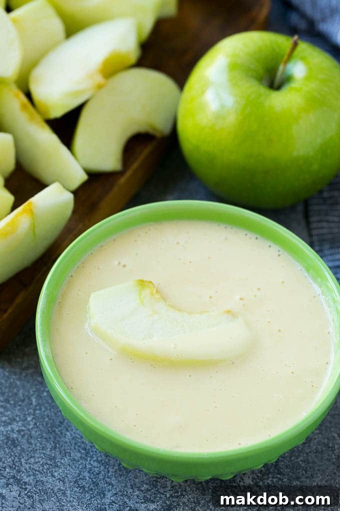 A single apple slice perfectly coated in a smooth, light batter, ready for frying.