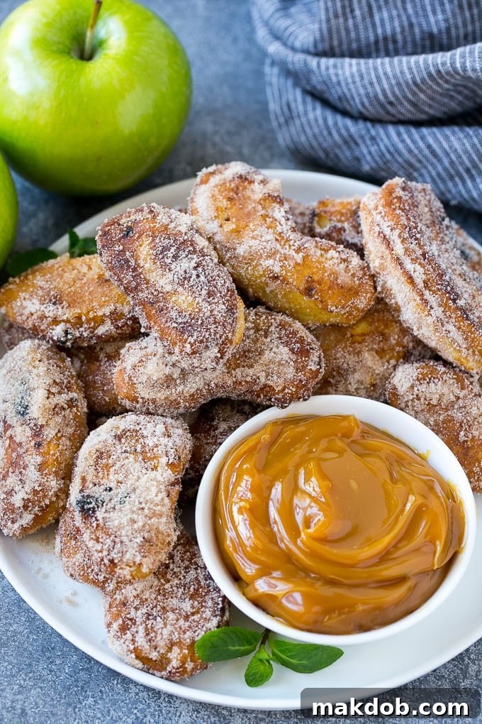 A generous pile of freshly made cinnamon sugar apple fries, accompanied by a small bowl of rich caramel sauce for dipping.