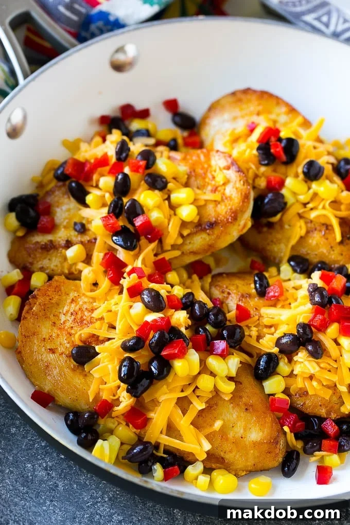 Fiesta Santa Fe Chicken 3 Seared chicken breasts topped with a generous layer of shredded cheese, black beans, corn kernels, and diced red bell peppers, ready for the oven.