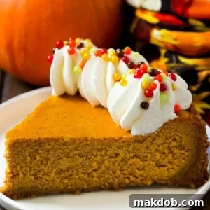 A slice of pumpkin cheesecake on a graham cracker crust, topped with whipped cream and sprinkles.