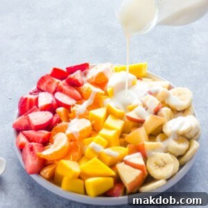 A fresh Fruit Salad with Healthy Honey Yogurt Sauce generously drizzled on top, featuring an assortment of colorful berries and melon for a nutritious treat.