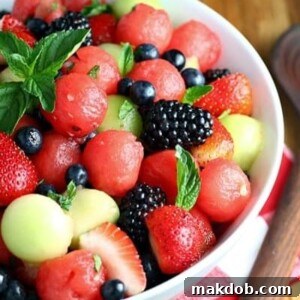 A vibrant Melon Berry Fruit Salad with Honey Lime Dressing, featuring colorful melon balls and mixed berries, garnished with fresh mint.