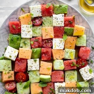 An artistic Melon Mosaic Salad, with square-cut melon pieces arranged beautifully and drizzled with a unique Hot Honey Vinaigrette for an unexpected flavor twist.