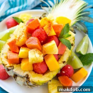 A vibrant Mexican Fruit Salad, combining an assortment of tropical fruits generously topped with a zesty chili lime seasoning for a sweet and savory kick.