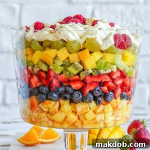 A beautiful seven-layer fresh fruit salad featuring distinct layers of colorful fruits like grapes, strawberries, and blueberries, perfect for an impressive presentation.