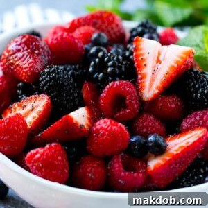 A refreshing Berry Fruit Salad, featuring a medley of raspberries, blueberries, blackberries, and strawberries, all coated in a light honey-based dressing.
