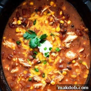 A vibrant pot of chicken taco soup, generously topped with creamy sour cream and shredded cheese, ready to be enjoyed.