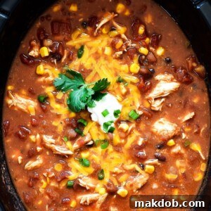 A appetizing pot of chicken taco soup, generously topped with sour cream and shredded cheese.