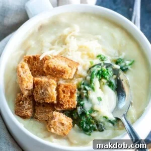 A decadent bowl of cheesy pesto potato soup, highlighting its creamy texture and rich green pesto swirls.