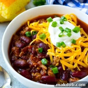 A hearty bowl of slow cooker turkey chili, beautifully topped with cool sour cream and shredded cheese.