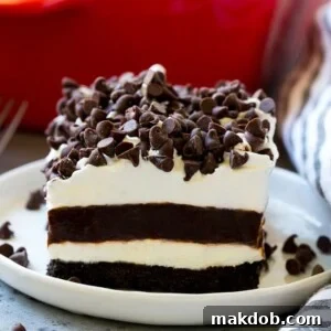 A slice of chocolate lasagna with layers of cookie crust, cheesecake and chocolate pudding.