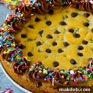 A cookie cake topped with chocolate frosting and sprinkles.