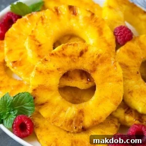 A plate of grilled pineapple slices garnished with raspberries and mint.