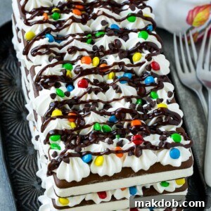 An ice cream sandwich cake with layers of the sandwiches, whipped topping and chocolate candy.