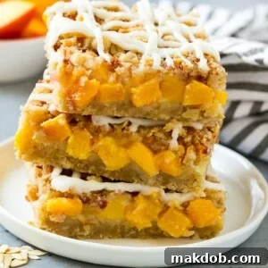 A stack of peach crumble bars topped with vanilla glaze.