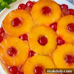 Pineapple upside down cake on a serving platter, garnished with fresh mint.
