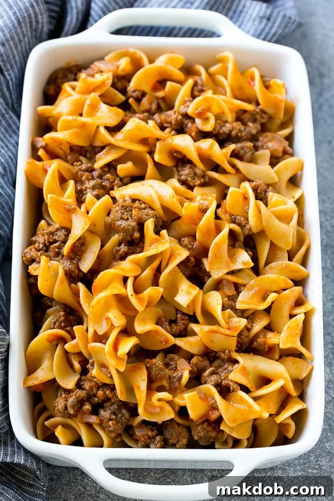 Ground beef and egg noodles tossed in tomato sauce, inside a baking dish.