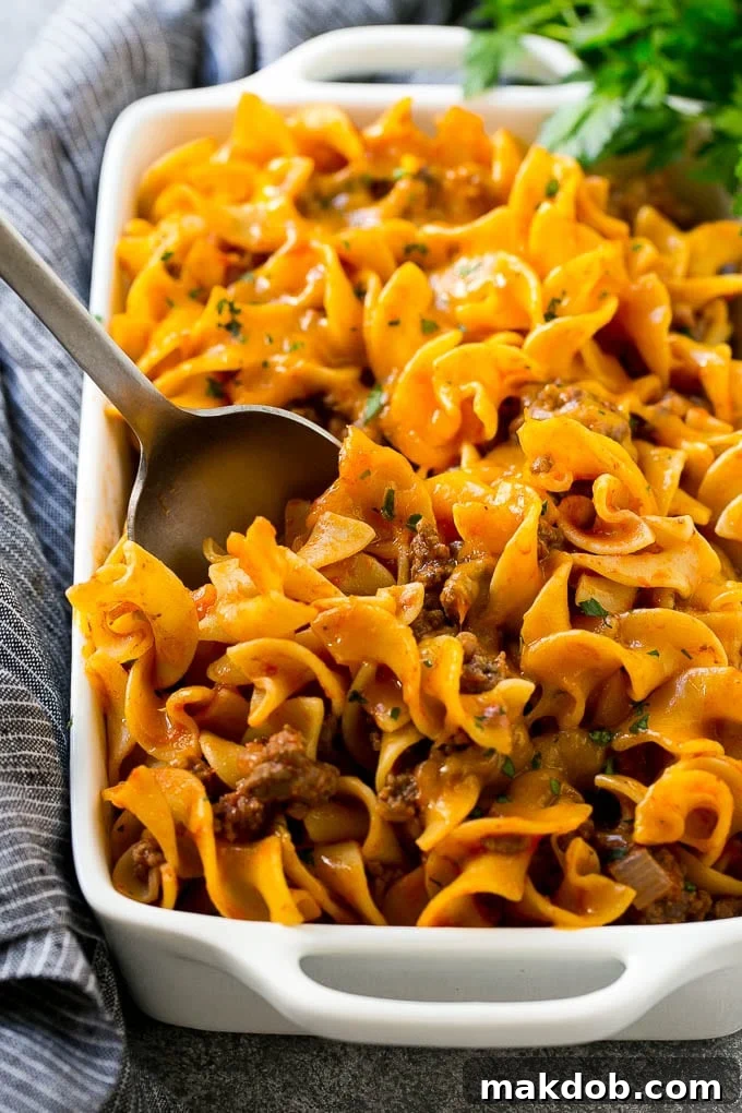 A pan of beef noodle casserole with a serving spoon in it.