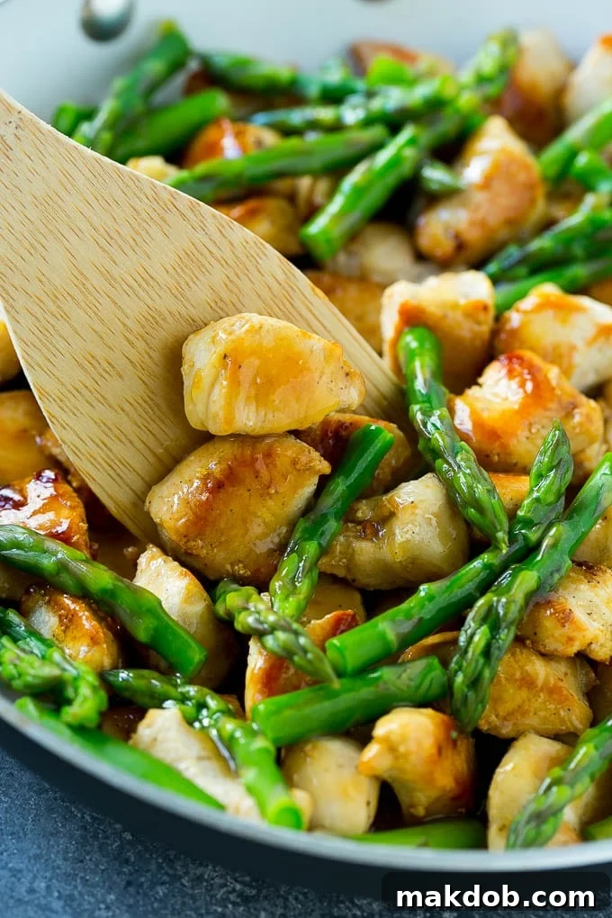 Speedy Chicken and Asparagus Stir Fry 4 Chicken and asparagus stir fry in a skillet with a serving spatula.