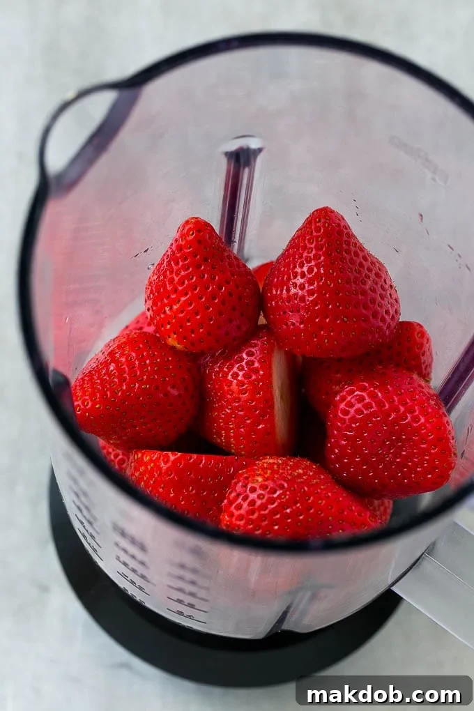 Strawberry Lemonade Recipe | Homemade Lemonade | Strawberry Drink Recipe #lemonade #strawberries #drink #dinneratthezoo Fresh, vibrant strawberries are placed into a blender alongside granulated sugar, ready to be transformed into a sweet, flavorful puree for a refreshing drink.