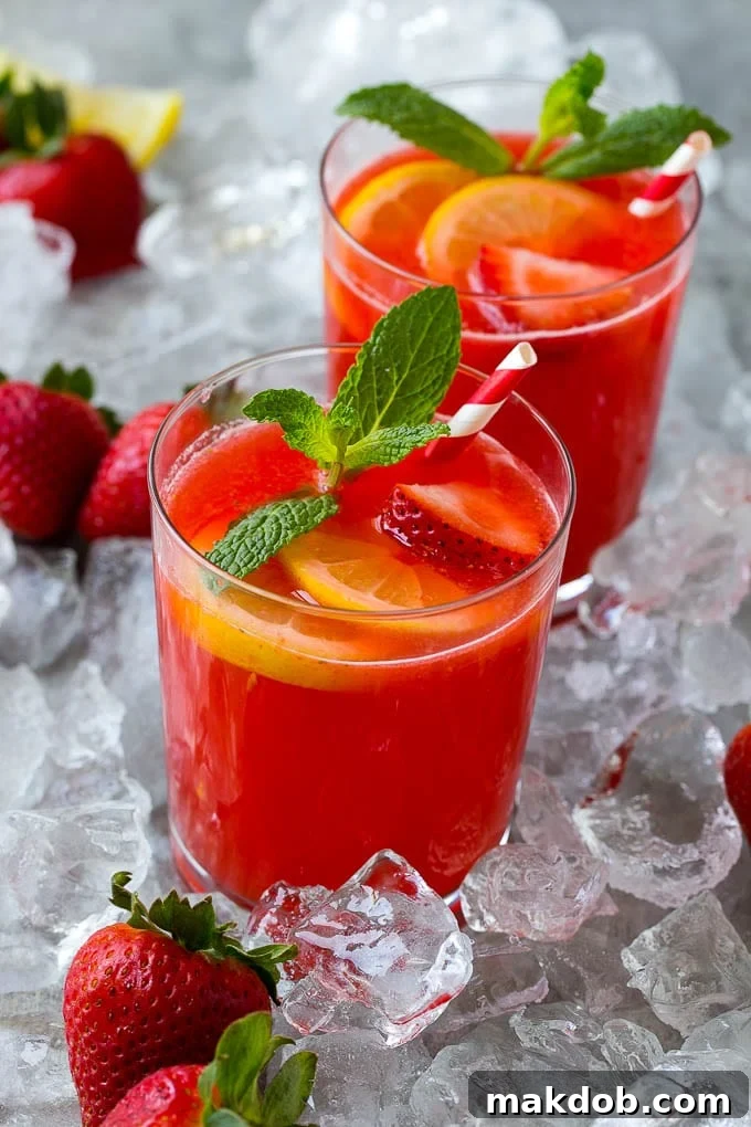 Strawberry Lemonade Recipe | Homemade Lemonade | Strawberry Drink Recipe #lemonade #strawberries #drink #dinneratthezoo Close-up of two glasses filled with ice-cold strawberry lemonade, garnished with fresh strawberry slices and vibrant lemon wedges, enticingly presented on a table.