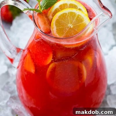 Blush Berry Zest 2 A pitcher of strawberry lemonade garnished with sliced lemons and mint.