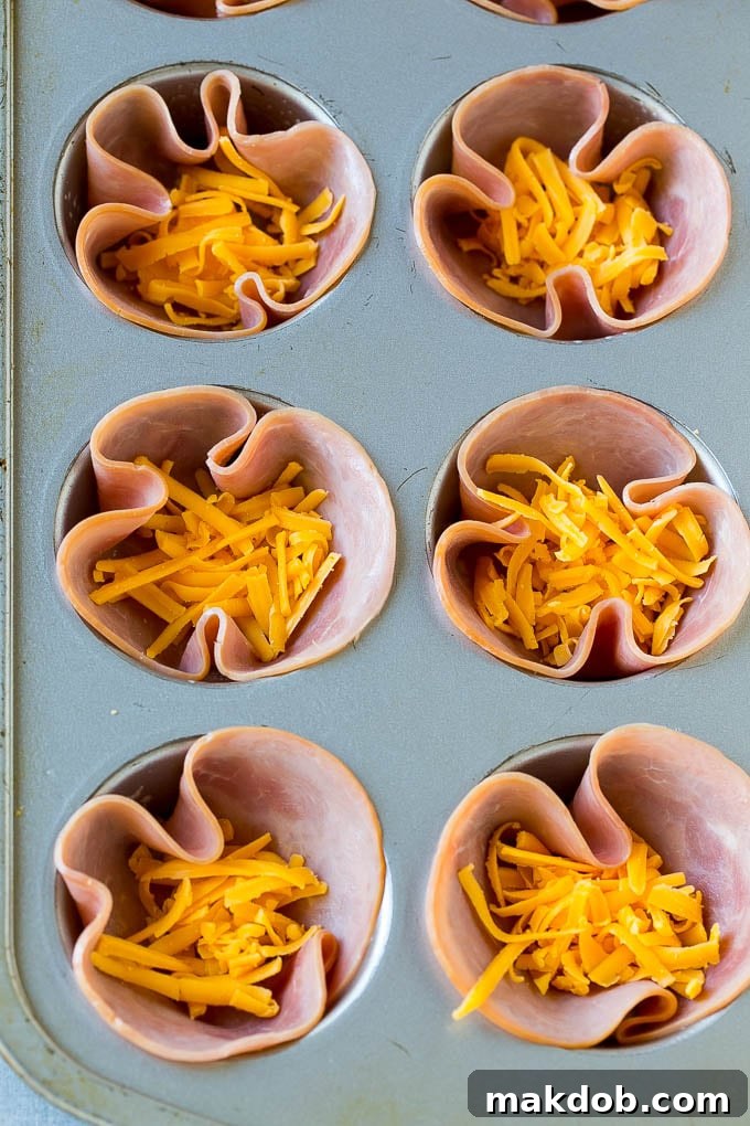 Ham and Egg Cups Base | Muffin Tin Breakfast Prep Ham slices pressed into a muffin tin, creating a base for ham and egg cups, topped with shredded cheese.