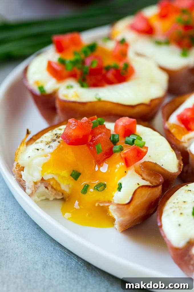 Cooked Ham and Egg Cup | Runny Yolk Option A perfectly baked ham and egg cup with a slightly runny yolk, garnished with fresh chives, showing its delicious texture.