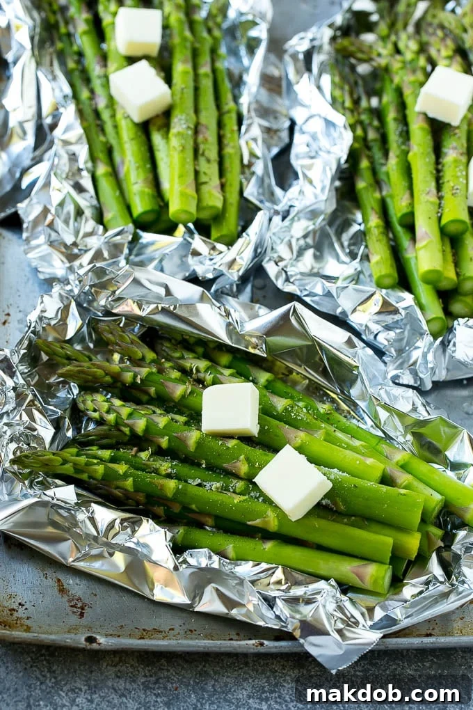 Raw asparagus stalks topped with butter and seasonings.