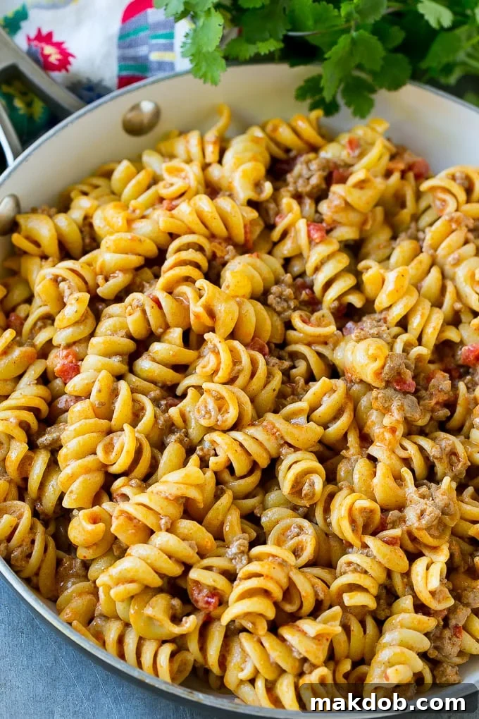 Rotini pasta mixed with ground beef and tomatoes in a creamy sauce.
