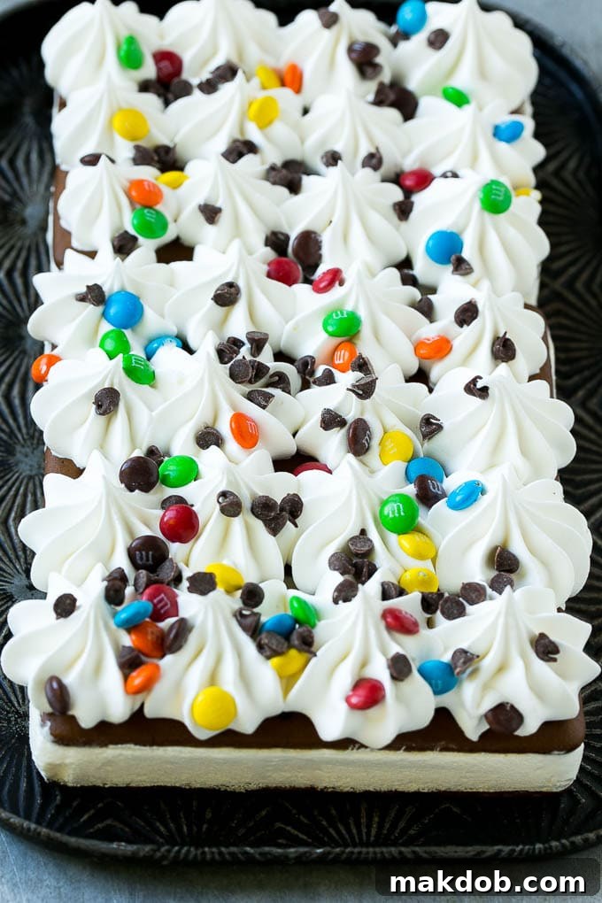 Ice cream sandwiches topped with whipped topping and candy in preparation for layering.