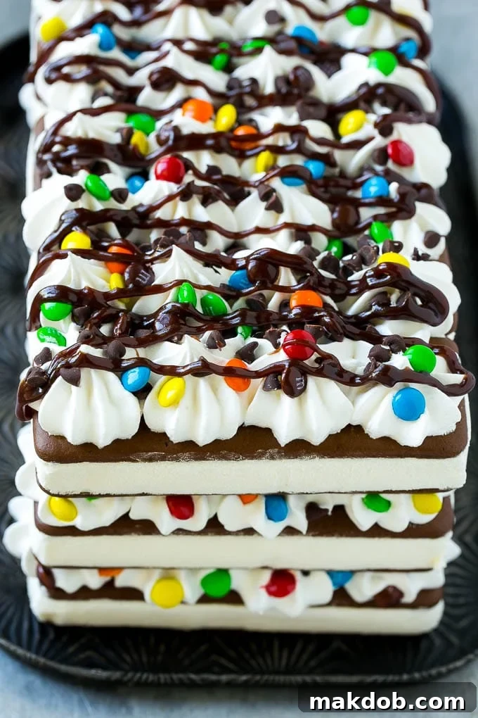 The front view of a beautifully decorated ice cream sandwich cake drizzled with rich fudge sauce.