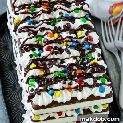 An ice cream sandwich cake with layers of the sandwiches, whipped topping and chocolate candy.
