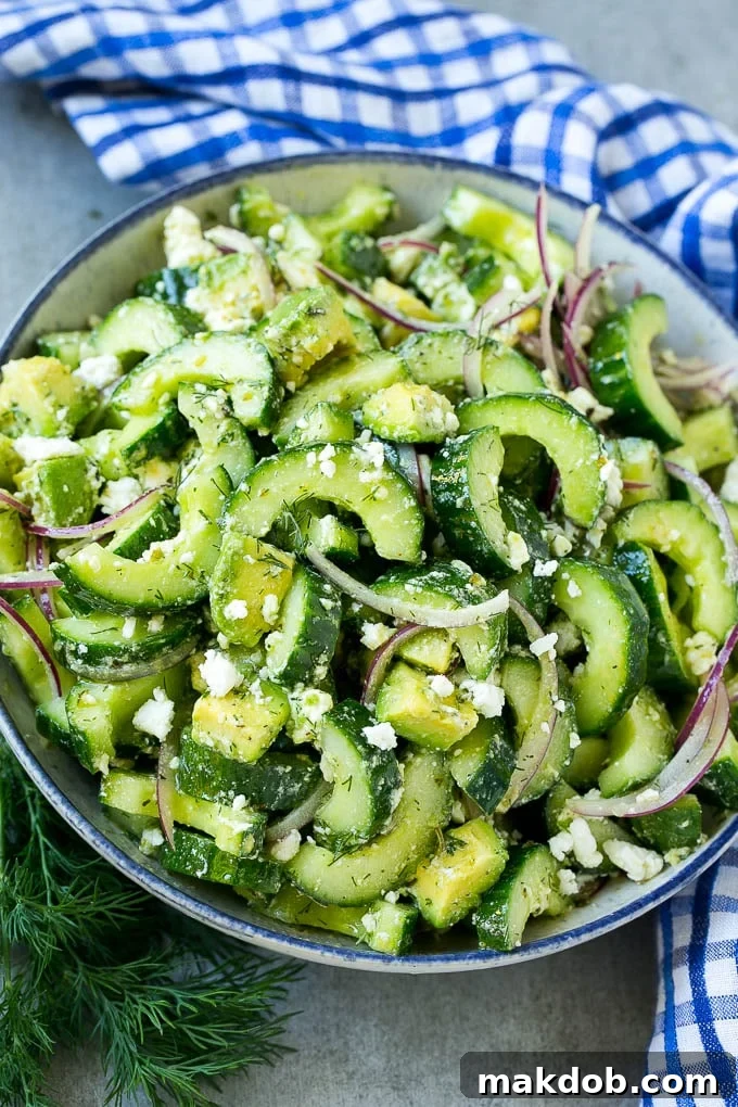 A generously sized bowl of cucumber feta salad, featuring vibrant green cucumbers, creamy avocado pieces, and delicate fresh dill, all perfectly coated in a light Greek dressing.