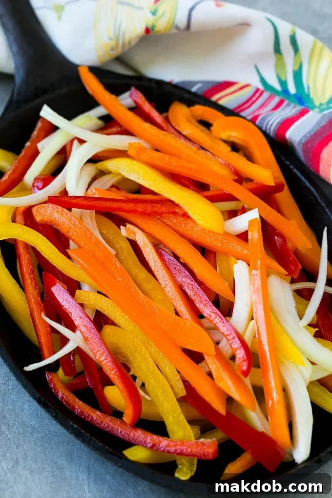 Vibrant slices of bell peppers and onions sizzling in a hot skillet, ready for the shrimp.