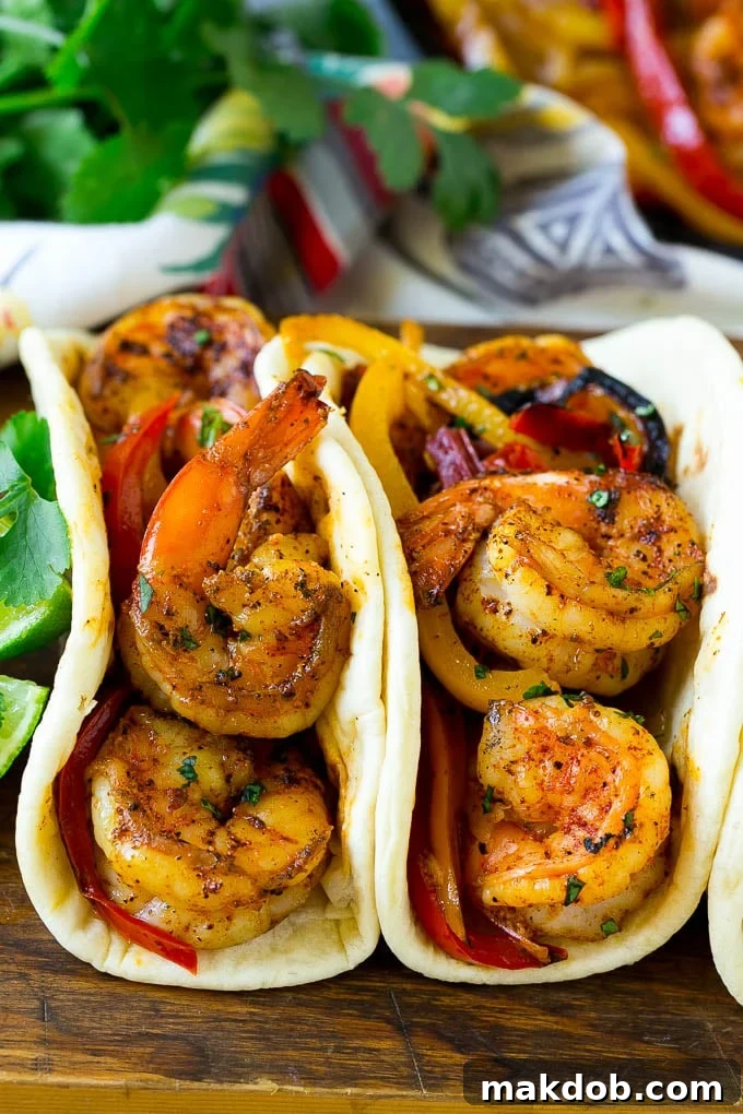Close-up of freshly assembled shrimp fajitas nestled inside soft flour tortillas, ready to eat.