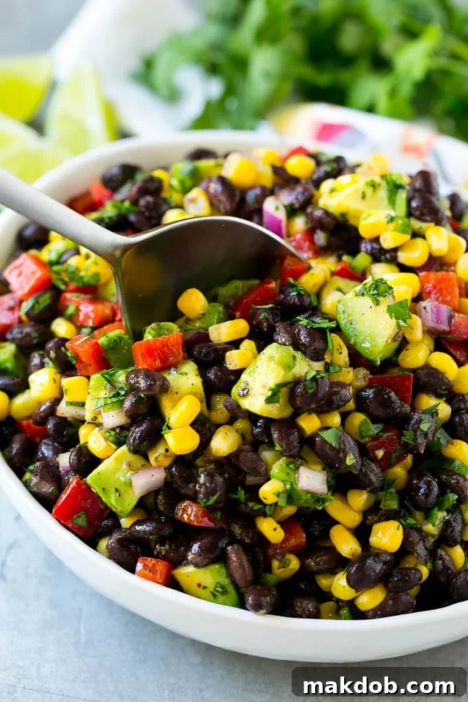 Ready-to-Serve Black Bean and Corn Salad A bowl of black bean and corn salad with a serving spoon, garnished with fresh cilantro.
