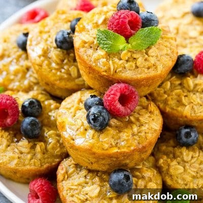 Baked oatmeal cups on a platter topped with maple syrup, berries and mint.