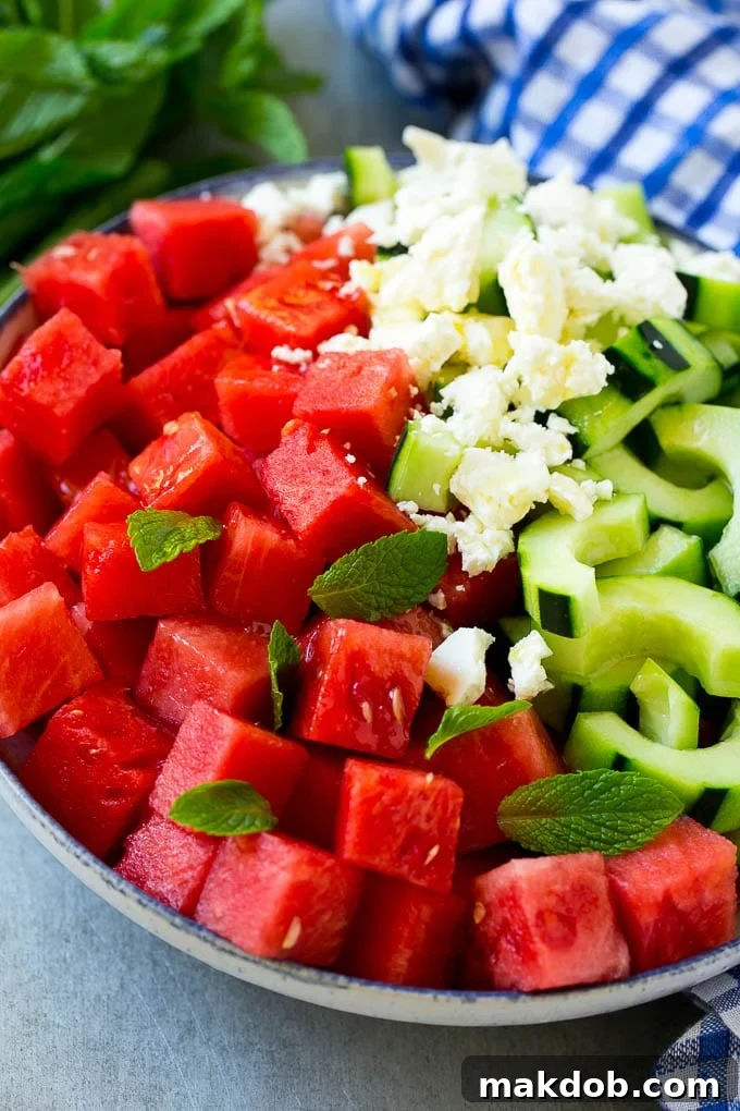 Watermelon, cucumber, feta cheese, and mint leaves artfully arranged in a bowl, glistening with a light drizzle of lime dressing, ready to be served.