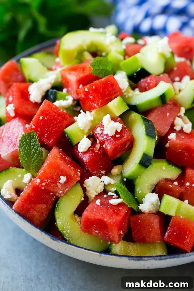 A vibrant bowl of watermelon salad, featuring bright red watermelon, crisp cucumbers, crumbled feta, and fresh mint, prepared in a serving bowl, ready to be enjoyed on a warm day.