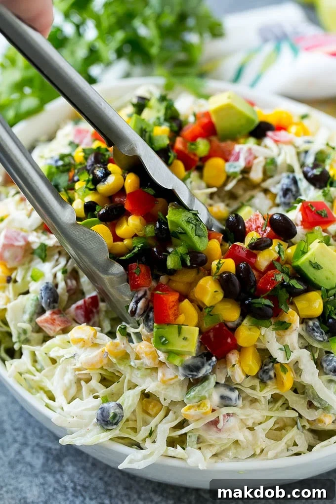 Mexican Coleslaw Recipe | Southwestern Coleslaw | Easy Coleslaw #coleslaw #mexicanfood #salad #dinneratthezoo A bowl of Mexican coleslaw with salad tongs in it.