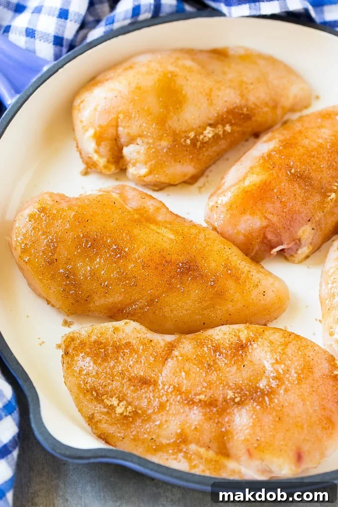 Boneless, skinless chicken breasts evenly coated in a rich brown sugar and spice mixture, ready for wrapping.