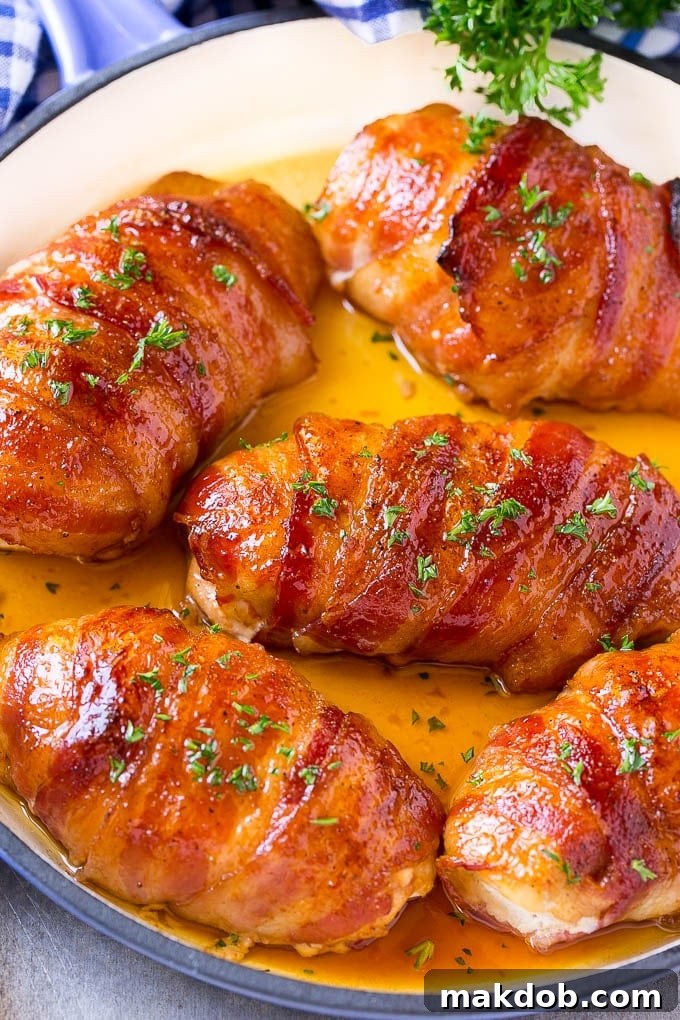 A baking pan filled with golden-brown bacon wrapped chicken, garnished with fresh parsley, freshly baked and ready to serve.