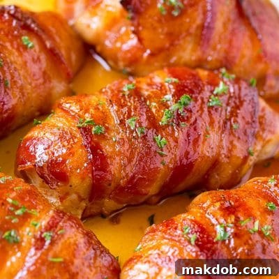 Bacon wrapped chicken breast with sauce in a skillet, garnished with fresh parsley.