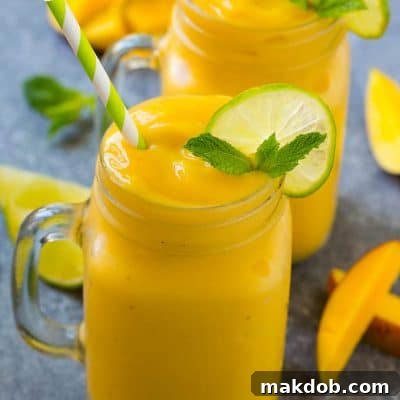 Mango smoothie in a mug topped with a slice of lime and mint sprig.